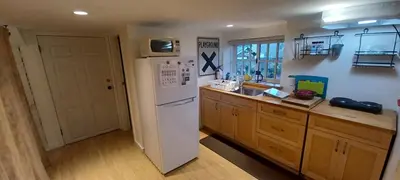 a kitchen with a white refrigerator and wooden cabinets at Rosewood Garden Studio in New Westminster