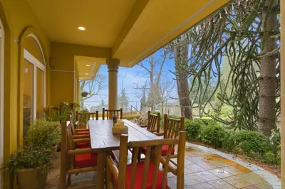 a porch with a wooden table and chairs on a patio at Entire Spanish Style Villa 5 Bedrooms near Ocean in West Vancouver