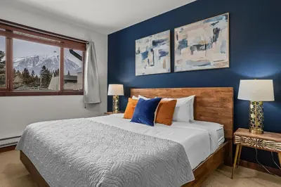 a bedroom with a bed with blue walls and a window at Heart of Canmore Condo managed by Little Sister Getaways in Canmore