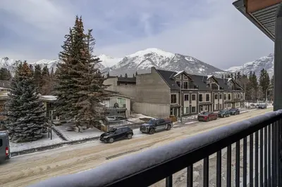 a view from a balcony of a town with snow covered mountains at Heart of Canmore Condo managed by Little Sister Getaways in Canmore