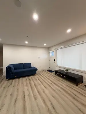 a living room with a blue couch and a large window at Downtown Vancouver Rooms - Walk to SkyTrain & BC Place, Free Parking & Fast Wi-Fi in Vancouver