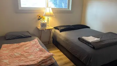 a bedroom with two beds and a table with a lamp at Downtown Vancouver Rooms - Walk to SkyTrain & BC Place, Free Parking & Fast Wi-Fi in Vancouver