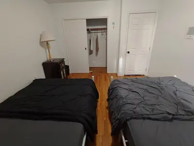 two beds in a bedroom with a closet and a door at Vancouver Private Rooms - Free Parking, Fast Wi-Fi, Easy Transit - 15 mins Downtown & 11 mins Airport in Vancouver