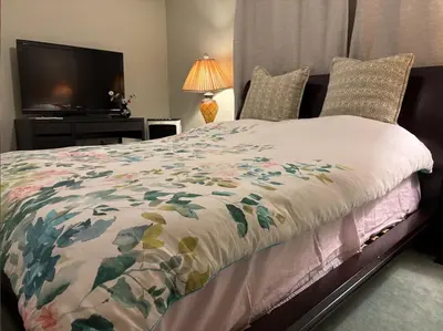 a bedroom with a bed with a flowered blanket and a television at Sweet Home in Aldergrove