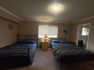 a bedroom with two beds and a lamp and a window at Surrey- Delta Budget Guest House - Private Rooms & Suites, Free Parking & Fast Wi-Fi in Surrey