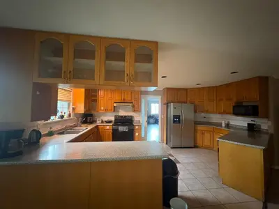a large kitchen with wooden cabinets and a refrigerator at Surrey- Delta Budget Guest House - Private Rooms & Suites, Free Parking & Fast Wi-Fi in Surrey