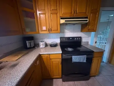 a kitchen with wooden cabinets and a black stove at Surrey- Delta Budget Guest House - Private Rooms & Suites, Free Parking & Fast Wi-Fi in Surrey