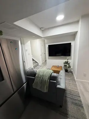 a living room with a couch and a flat screen tv at Brand New 1 Bedroom Basement Suite in Southwest in Edmonton