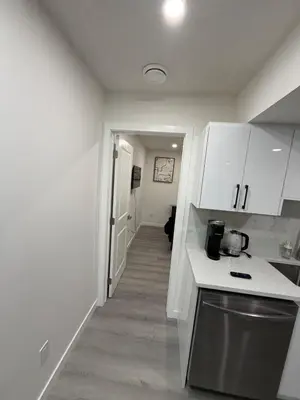 a kitchen with white cabinets and a hallway at Brand New 1 Bedroom Basement Suite in Southwest in Edmonton