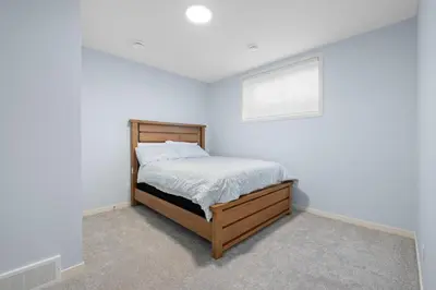 a bedroom with a bed in a white room at Cozy 2 Bedroom Private Basement Suite SW Calgary in Calgary