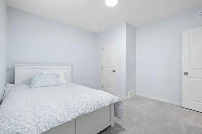 a white bedroom with a bed and a closet at Cozy 2 Bedroom Private Basement Suite SW Calgary in Calgary