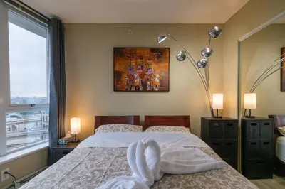 a bedroom with a bed and a painting on the wall at Modern Central Location with Pool Sauna & Jacuzzi in Vancouver