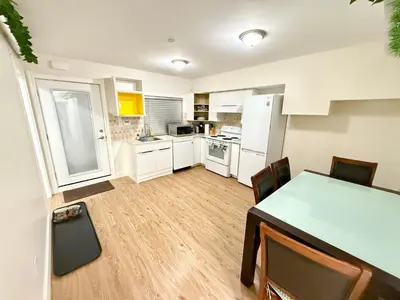 a kitchen with white cabinets and a table and chairs at Private Guest Suite, Two Parking Spaces in Maple Ridge District Municipality