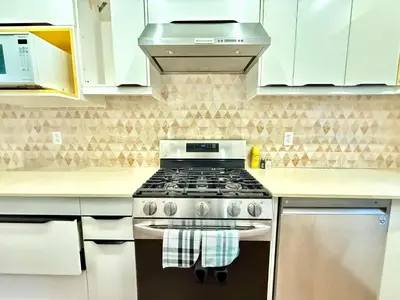 a stove top oven in a kitchen with white cabinets at Private Guest Suite, One Parking Space in Maple Ridge District Municipality