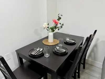 a black table with black plates and a vase with flowers at Comfort 2 BR Vancouver! in Vancouver