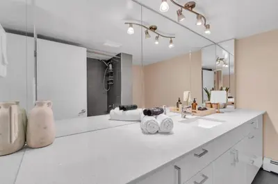 a white bathroom with a sink and a mirror at 2B 17 Ave King Suite in Calgary