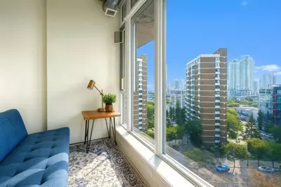a room with a blue couch and a large window at Cozy Downtown Retreat with Stunning River Views in Calgary