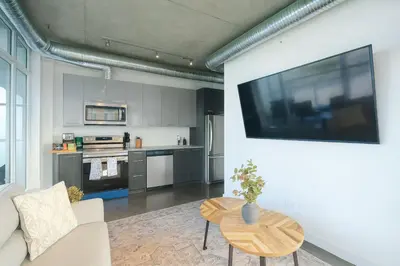 a living room with a couch and a tv on a wall at Cozy Downtown Retreat with Stunning River Views in Calgary