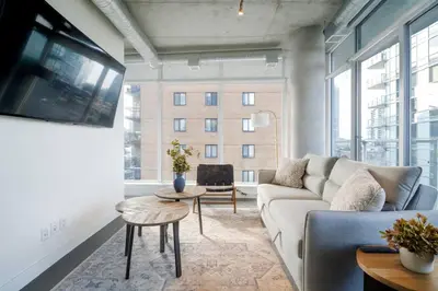 a living room with a couch and a large window at Cozy Downtown Retreat with Stunning River Views in Calgary