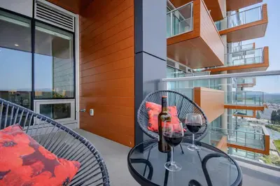 a glass table with two wine glasses on a balcony at 418 Frontier in Calgary