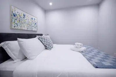 a white bed with a teddy bear sitting on top of it at 418 Frontier in Calgary