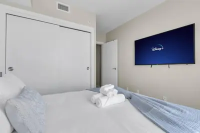 a bedroom with a white bed with a tv on the wall at 1409 Guardian South in Calgary