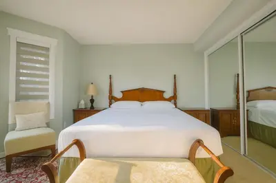 a bedroom with a large white bed and a chair at Shiraz Place in Calgary