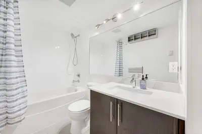 a white bathroom with a sink and a toilet at Stylish 2BR Downtown Condo By Arena Free Parking in Vancouver