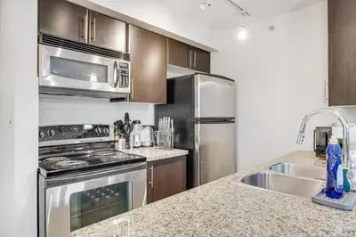 a kitchen with stainless steel appliances and a sink at Stylish 2BR Downtown Condo By Arena Free Parking in Vancouver