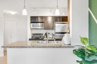 a kitchen with a sink and stainless steel appliances at Stylish 2BR Downtown Condo By Arena Free Parking in Vancouver