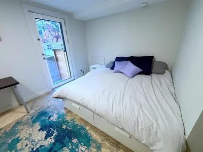 a white bedroom with a bed and a window at Coastal Drift Sooke in Sooke