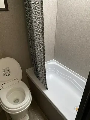 a bathroom with a toilet and a shower curtain at Warm new Jayco trailer with comfy queen bed in Aldergrove