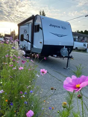 a trailer parked in a parking lot with flowers at Warm new Jayco trailer with comfy queen bed in Aldergrove