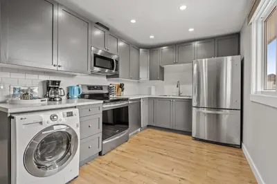 a kitchen with stainless steel appliances and a washer and dryer at Entire Home - 2 Separate Units in Calgary
