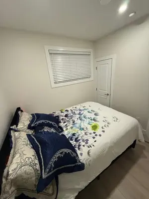 a bedroom with a bed with a blanket and a window at The ideal place for professionals in Prince George