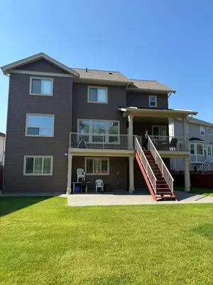 a large house with a porch and a person standing on the balcony at Modern 2 Bedroom Suite Private & Fully Furnished in Prince George