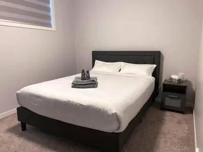 a bedroom with a bed with a black frame and white sheets at Modern 2BR Suite with Private Yard in Calgary