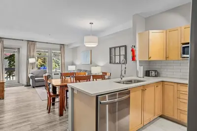 an open kitchen and dining room with a table and a kitchen at Cedar and Stone - 2 Bed 2 Bath Condo with Heated Pool and Hot Tub in Canmore