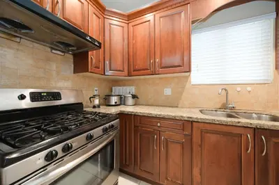 a kitchen with wooden cabinets and a stove and a sink at Cozy Room with Private Washroom in Central Location in Vancouver