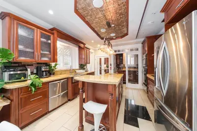 a kitchen with wooden cabinets and a large island at Luxurious & Spacious Mansion next to Oakridge Mall in Vancouver