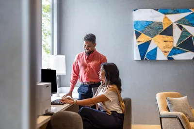 a man and a woman sitting at a desk with a computer at Hyatt Place Vancouver/Metrotown in Burnaby