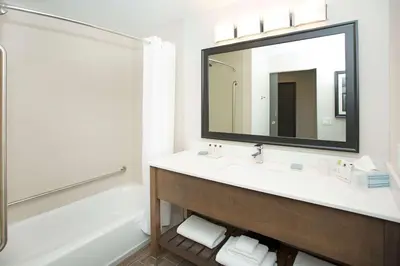 a bathroom with a sink and a tub and a mirror at Wingate by Wyndham Calgary Airport in Calgary