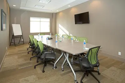 a conference room with a long table and green chairs at Wingate by Wyndham Calgary Airport in Calgary
