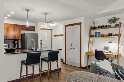 a kitchen and living room with a counter and chairs at Modern 1 Bedroom Retreat with Sofa Bed Comfort & Convenience Combined in Canmore