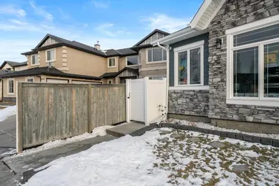 a house with a wooden fence in the snow at Waterfront 1BR Suite Private and Modern and Queen Bed in Airdrie