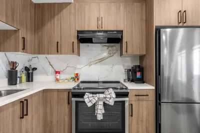 a kitchen with a stove and a stainless steel refrigerator at Waterfront 1BR Suite Private and Modern and Queen Bed in Airdrie