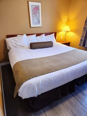 a large bed in a hotel room with a pillow on it at Fox Creek Inn in Fox Creek