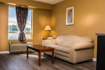 a living room with a chair and a table and a window at Fox Creek Inn in Fox Creek