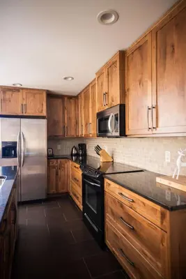 a kitchen with wooden cabinets and a stainless steel refrigerator at Arnica Chalet 2bd 2bath Ski In Out Silver Star in Vernon