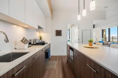 a kitchen with white counter tops and wooden cabinets at Dt Spacious and Vibrant | Kng Bed| Outdoor patio in Calgary